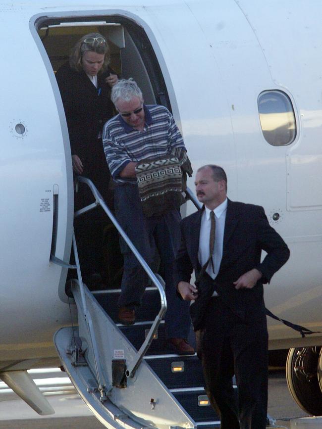 Paul Ronald Goldsmith is escorted by police after returning to Tasmania from Western Australia at Devonport Airport.