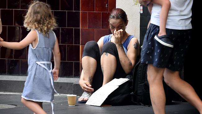 Young children with their parents look at a beggar on Swanston Street in December last year. Picture: Nicole Garmston