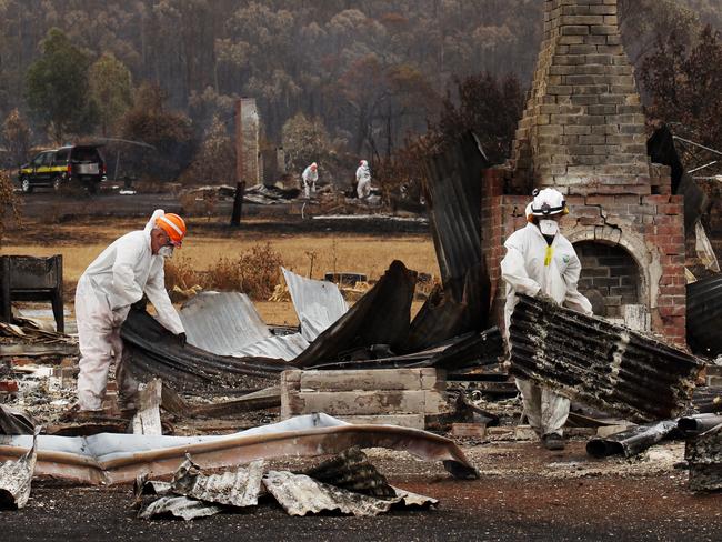 Sifting through the rubble of a destroyed property after the 2013 Dunalley bushfire.