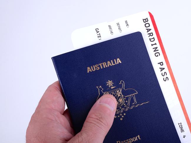 A man holds a new Australian passport with a boarding pass inserted inside the document