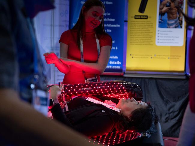 A person lays in a red light wrap at the Dr. Fuji / Acigi booth  in the Venetian Expo Center during the Consumer Electronics Show (CES) in Las Vegas, Nevada on January 9, 2024. (Photo by Brendan Smialowski / AFP)