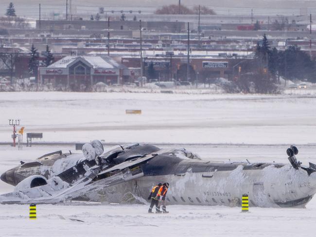 Airport workers survey the site of a Delta Air Lines plane crash at Toronto Pearson International Airport. Picture: Getty Images via AFP