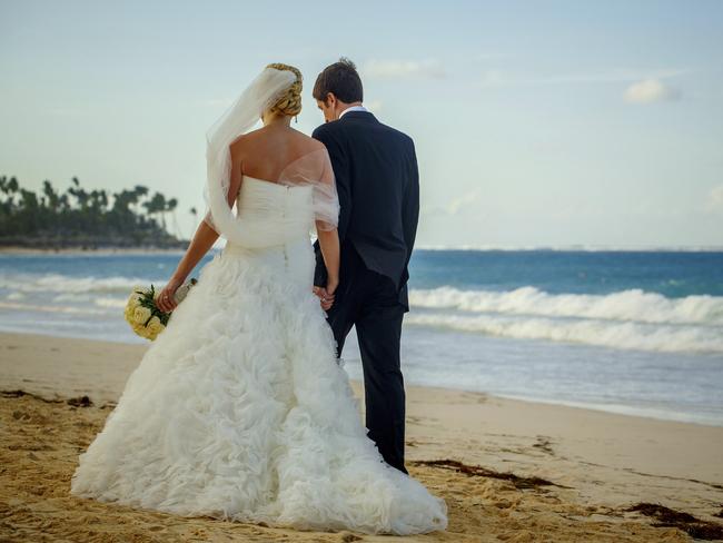 Bride and groom walk on the beach