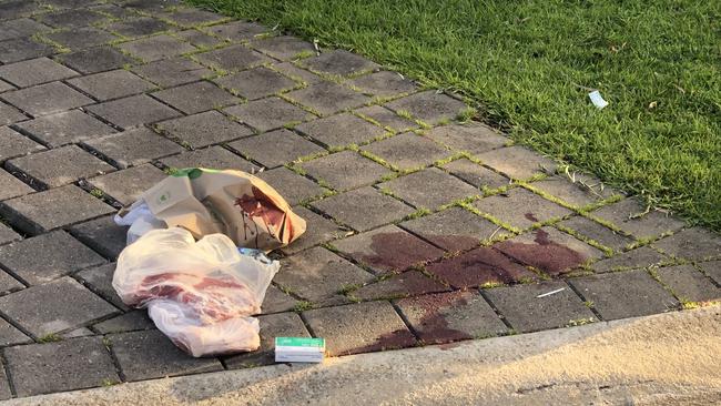 Fresh bloodstains remained on the driveway next to a bloodied shopping bag on Sunday morning.