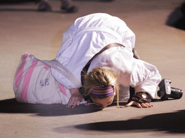 A woman kisses the ground after stepping off the Carnival ship Triumph at the Alabama Cruise terminal in Mobile on February 14, 2013. Picture: AFP