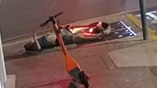 An eScooter rider lies motionless on the ground after face planting into the footpath at the corner of Smith and Knuckey Sts in this still from CCTV footage (above). Picture: Facebook/Supplied