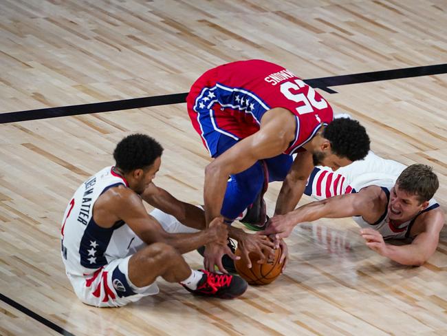 LAKE BUENA VISTA, FLORIDA - AUGUST 05:  Ben Simmons #25 of the Philadelphia 76ers goes for a loose ball with Jerome Robinson #12 and Moritz Wagner #21 of the Washington Wizards during the first half of an NBA basketball game at The Arena at ESPN Wide World Of Sports Complex on August 5, 2020 in Lake Buena Vista, Florida. NOTE TO USER: User expressly acknowledges and agrees that, by downloading and or using this photograph, User is consenting to the terms and conditions of the Getty Images License Agreement. (Photo by Ashley Landis-Pool/Getty Images)