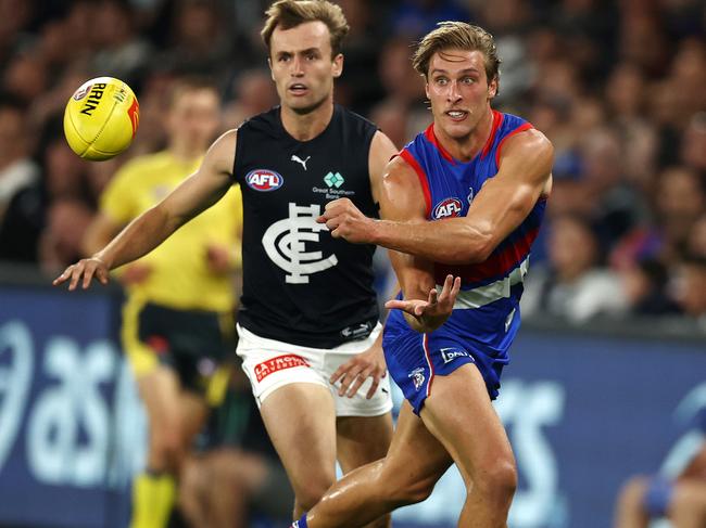 MELBOURNE.  24/03/2022.   AFL. Round 2.  Western Bulldogs vs Carlton at the Marvel Stadium .  Bulldog Roarke Smith clears by hand in front of Lochie OÃBrien of the Blues   . Photo by Michael Klein