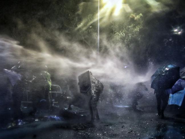 Students hit by a water cannon sprayed by police during a clash at Chinese University in Hong Kong. Picture: AP