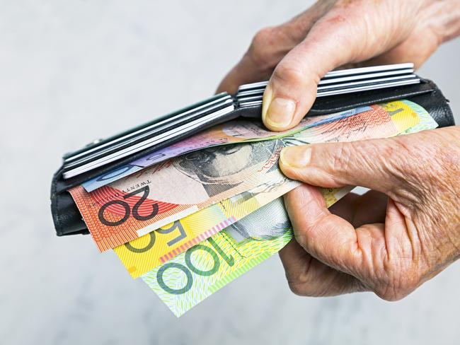 Close-up, senior female hands taking Australian banknotes (cash, currency) from purse containing many credit cards.  Horizontal, studio, copy space. Money generic