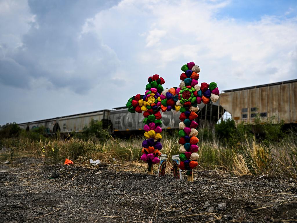 Cross and candles are kept at the spot where a tractor-trailer was discovered with migrants inside. Picture: AFP