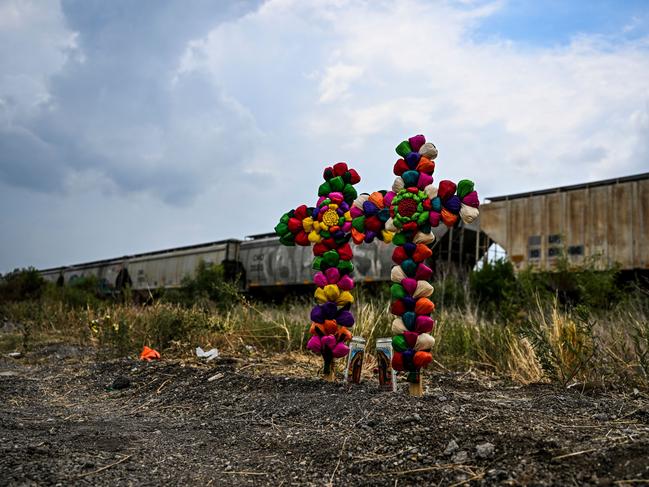 Cross and candles are kept at the spot where a tractor-trailer was discovered with migrants inside. Picture: AFP