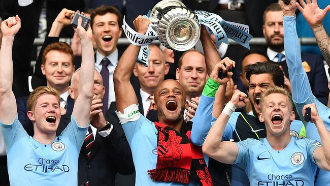 Manchester City captain Vincent Kompany (C) lifts the winner's trophy as the players celebrate victory. Picture: AFP.