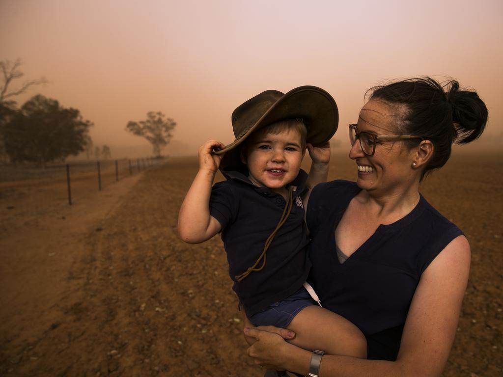 James Cox, 2, is carried by his mother Katie Cox in a dust storm. Their father Brad Cox is the fourth generation farmer on his family's property near Collie, north of Dubbo. Currently in the midst of the worst drought their worst drought on record, they farm sheep, cattle and grain. Picture: Dylan Robinson