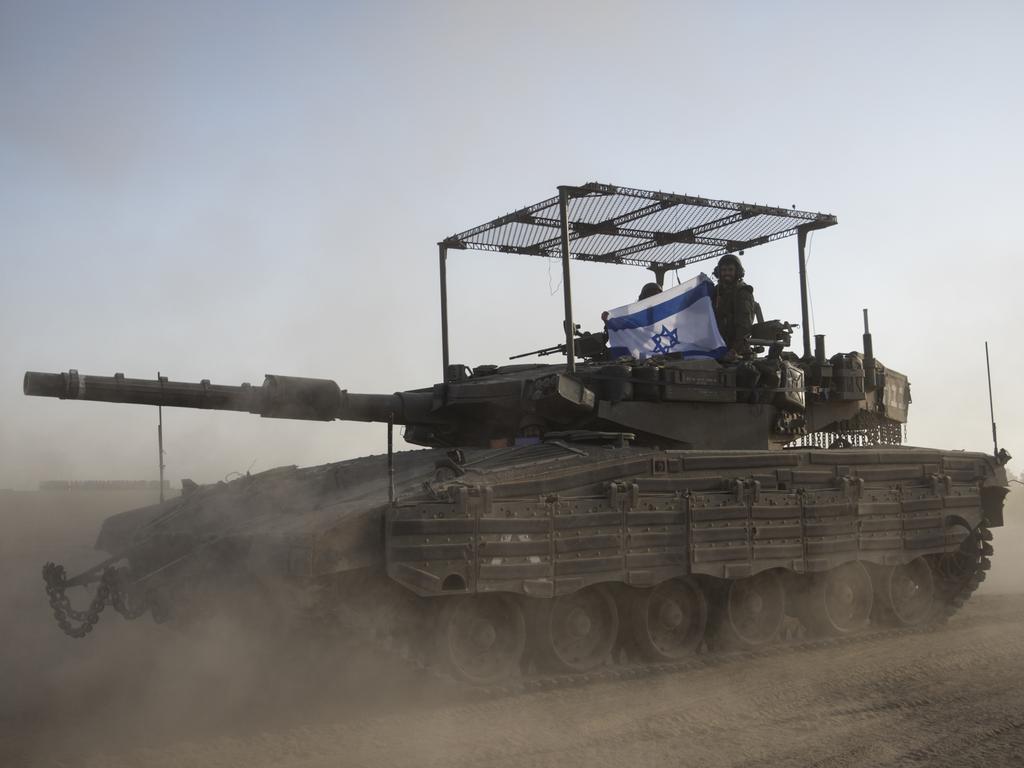 Israeli soldiers hold an Israeli flag on a tank that is moving along the border with Gaza Strip in Southern Israel. Picture: Getty Images