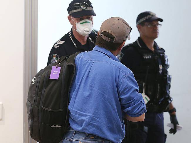 Federal and Queensland police greeting passengers of a Qantas flight coming in from Sydney to check they know the quarantine rules. Picture: Stewart McLean