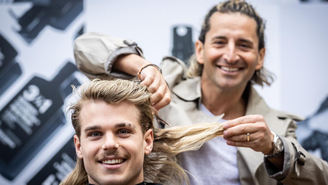 Western Bulldogs star Bailey Smith getting his mullet trimmed by hairdresser Joey Scandizzo at King's Domain. Picture: Jake Nowakowski