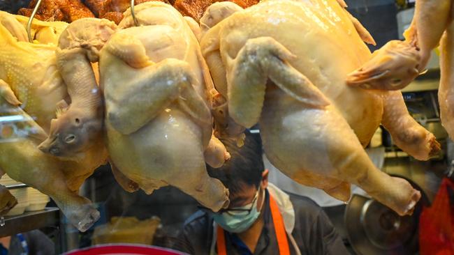 Chickens are displayed in the window as a vendor prepares chicken rice for customers at a hawker centre in Singapore. Picture: Roslan Rahman/AFP