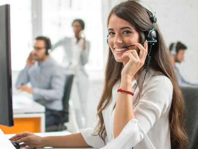 Young friendly operator woman agent with headsets working in a call centre.