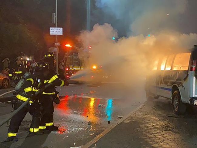 Firefighters work to contain the flames from a New York City Police Department van ablaze in the Brooklyn borough of New York. Picture: AP