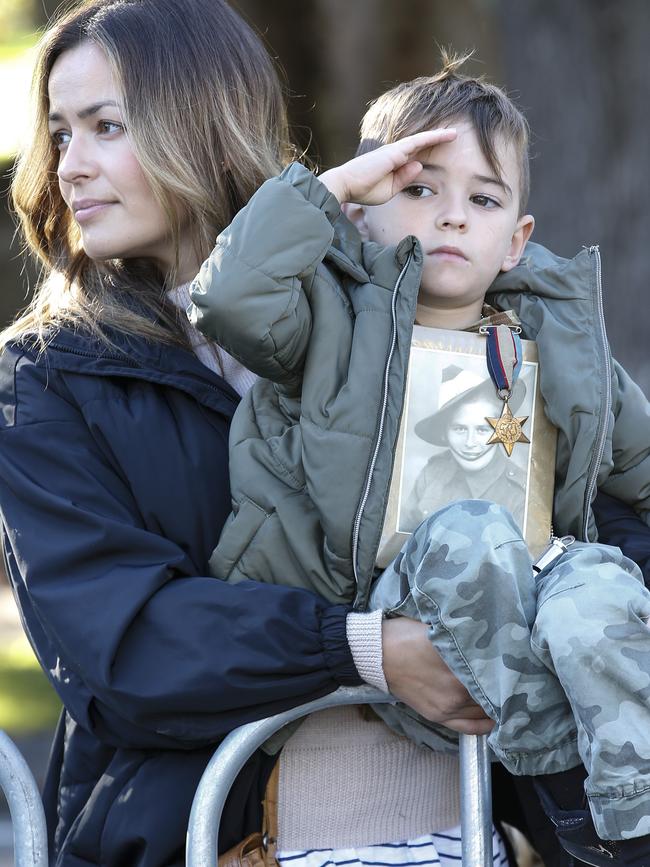 Taylor, 5, salutes the veterans while holding a photo of his WWII Digger great-grandfather. Picture: David Caird