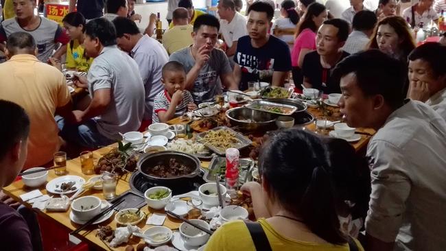 People eat dog meat at a restaurant during China's most notorious dog meat festival while butchers hack slabs of canines and cooks fry the flesh. Picture: AFP