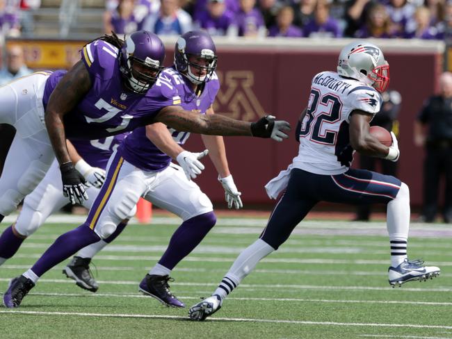 New England Patriots strong safety Devin McCourty, right, slips past Minnesota Vikings offensive tackle Phil Loadholt after intercepting a pass.