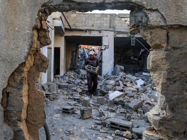 A man carries salvaged concrete blocks inside a building hit in an Israeli strike in the Bureij camp for Palestinian refugees in Gaza. Picture: Eyad Baba/AFP