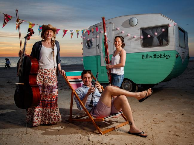 Are We There Yet? Adelaide Symphony Orchestra musicians Gemma Phillips (cello), Dean Newcomb (clarinet) and Jackie Newcomb (contrabassoon) with the Newcomb’s caravan “Billie Holiday” at Seacliff. Picture: Matt Turner.