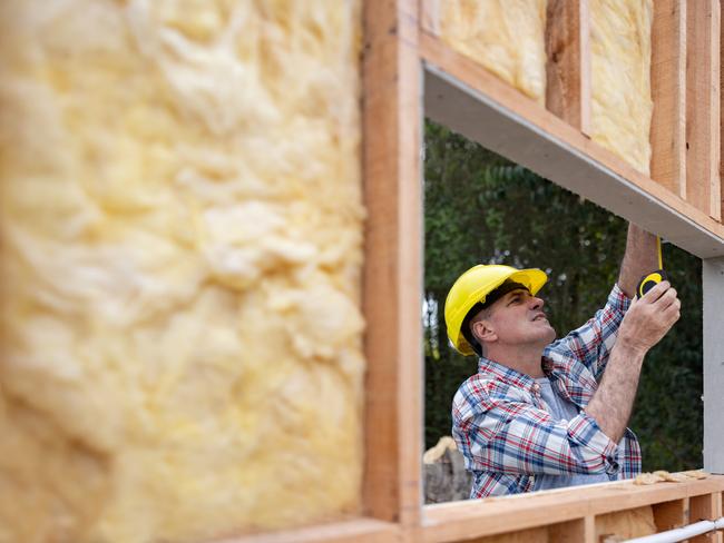 Construction worker taking measurements while building a house with insulation