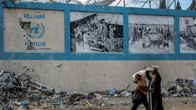 People walk past the damaged Gaza City headquarters of the United Nations Relief and Works Agency for Palestine Refugees.