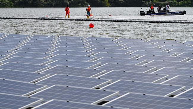 Workers install solar panels to build a floating solar power farm on Tengeh reservoir in Singapore, covering an area the size of 45 football fields. Picture: AFP