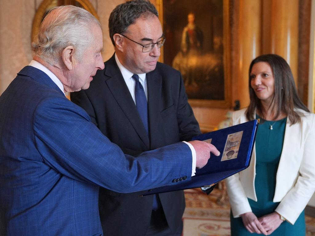 King Charles III (L) is reacts as Bank of England Governor Andrew Bailey (C) and Bank of England's Chief Cashier Sarah John present him with the first bank notes featuring his portrait. Picture: AFP