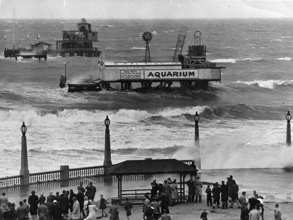 What remained of the Glenelg jetty after the storm on April 11, 1948. The decking formerly extended from the right of the right-hand lamp standard past the left end of the Aquarium to the kiosk in the background. Picture: The Advertiser