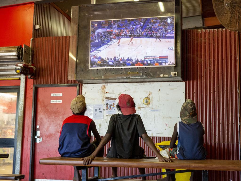 Three young Wurrumiyanga boys watch the basketball on the big screen in the lunch area. Picture: Floss Adams.