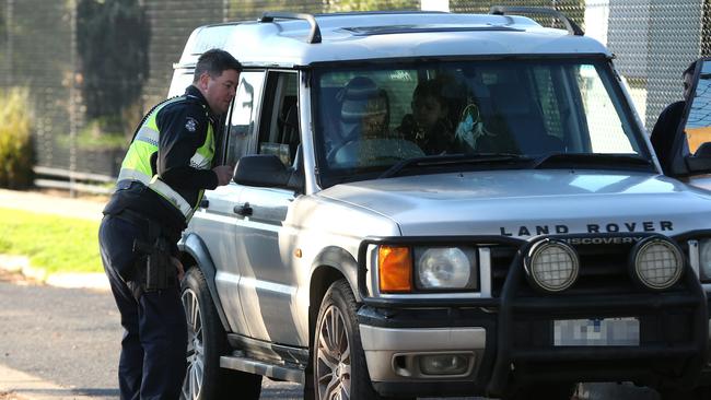 Sgt Stephen Little speaks with a driver outside Glenroy West Primary School. Picture: Hamish Blair