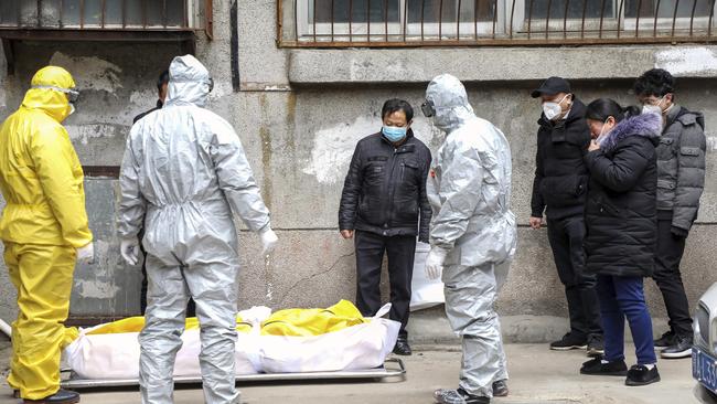 Funeral home workers remove the body of a person suspected to have died from the coronavirus outbreak from a residential building in Wuhan back in February.
