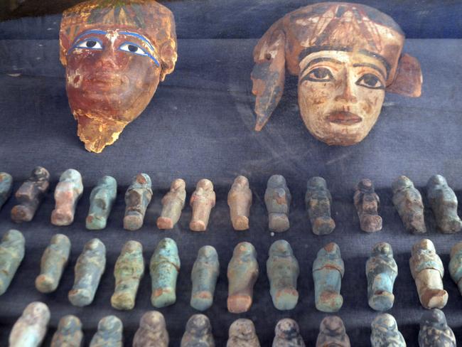 A picture taken on December 9, 2017 shows ancient Egyptian wooden funerary masks and small statuettes found in and retrieved from the newly discovered "Kampp 150" tomb at Draa Abul Naga necropolis on the west Nile bank of the southern Egyptian city of Luxor, about 650 kilometres (400 miles) south of the capital Cairo. / AFP PHOTO / STRINGER