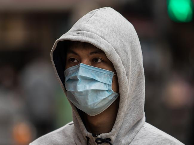 A man wearing a protective face mask crosses a street in Hong Kong on February 9, 2020, as a preventative measure after a coronavirus outbreak which began in the Chinese city of Wuhan. - The previously unknown virus has caused alarm because of its similarity to SARS (Severe Acute Respiratory Syndrome), which killed hundreds across mainland China and Hong Kong in 2002-2003. (Photo by DALE DE LA REY / AFP)