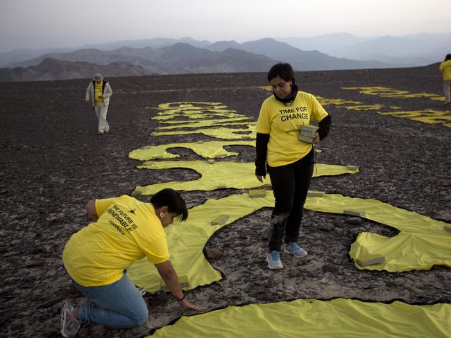 Greenpeace activists arrange the letters delivering the message "Time for Change: The Future is Renewable" next to the hummingbird geoglyph in Nazca, Peru. (AP Photo/Rodrigo Abd)