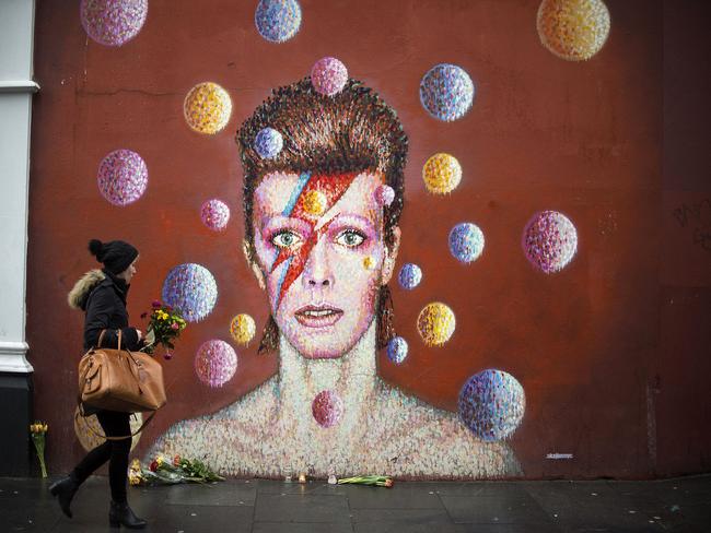 Flowers are left below a mural of Bowie on the wall of a Morley’s store in Brixton, London, the singer’s birthplace.