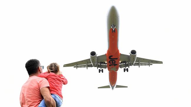 A father and daughter look on as a Jetstar aircraft passes overhead. Residents in dozens of Brisbane suburbs say plane noise is now a major issue for them. Picture: AAP/Dave Hunt