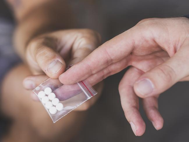 Drug dealer selling ecstasy pills to a drug addict drug dealer istock