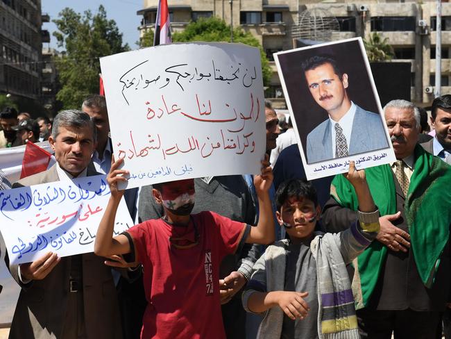 Syrians wave the national flag and wave portraits of President Bashar al-Assad as they gather in Aleppo's Saadallah al-Jabiri square to condemn the strikes.