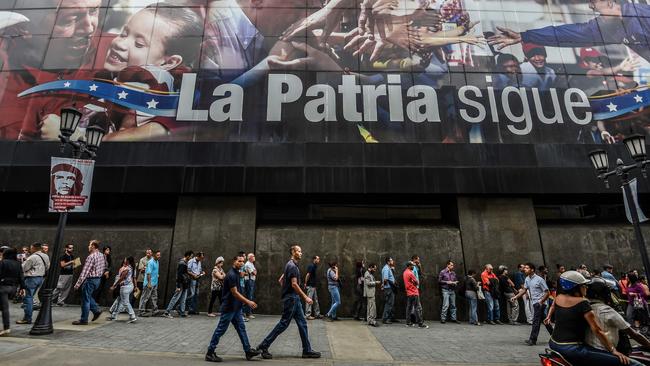 People queue to withdraw money from an ATM in Caracas. Picture: AFP/Juan Barreto