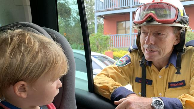 Former prime minister Tony Abbott, talks to Taje Lawson, 3, from Narrabeen, after his family bumped into the volunteer rural firefighter at Milton while he was on duty fighting bush fires on the NSW south coast. Picture: Sarah Lawson