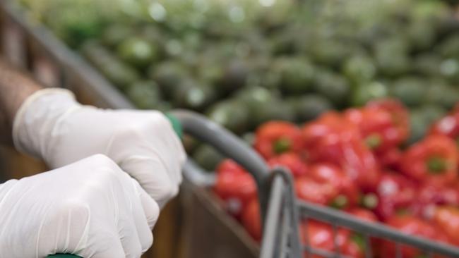 A man's hands on shopping cart wearing gloves to protect himself from infection.