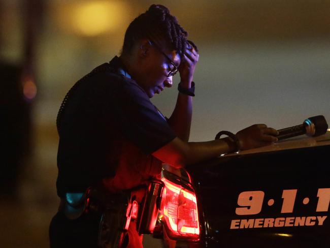 A Dallas police officer, who did not want to be identified, takes a moment as she guards an intersection in the early morning after the shooting. The Police chief said the force is “heartbroken” over the events. Picture: LM Otero