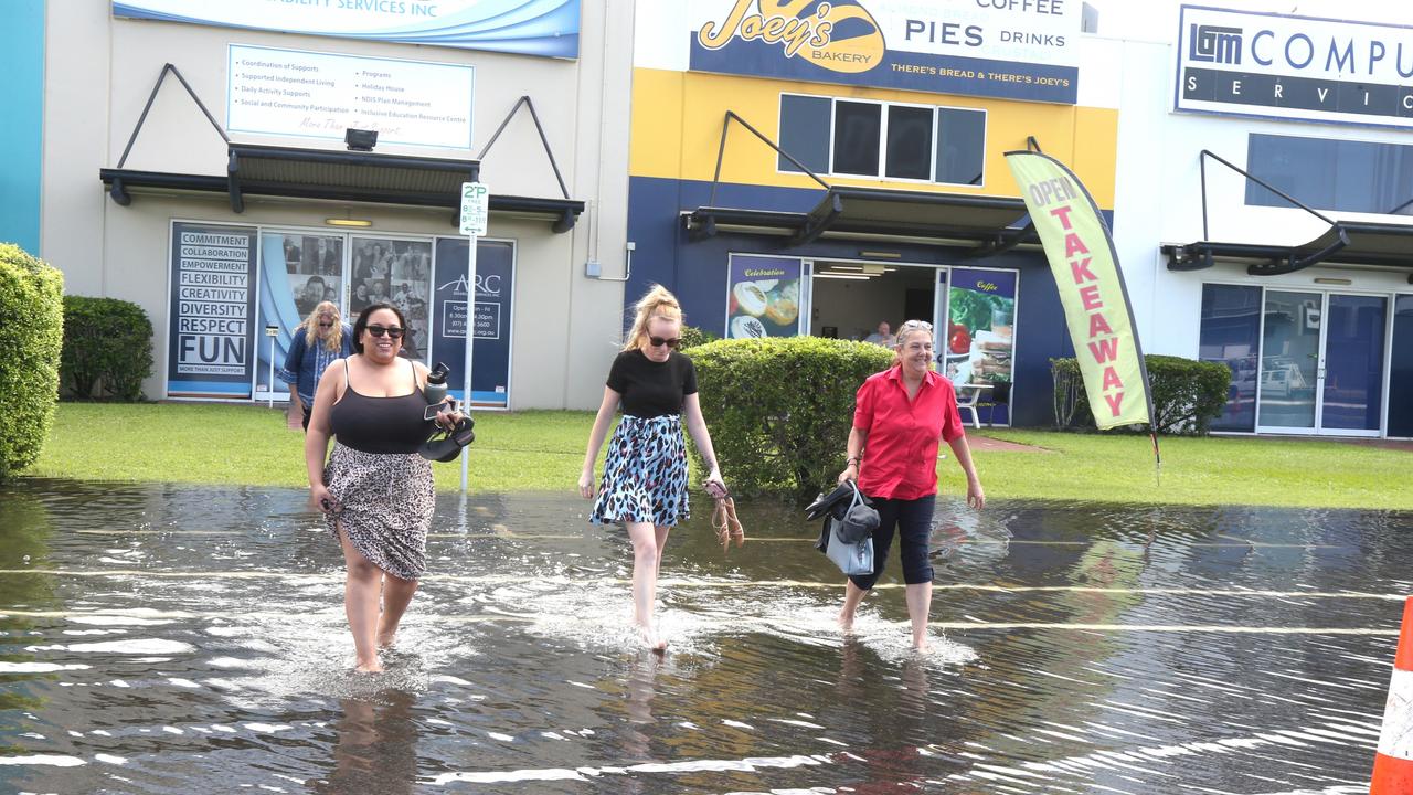 Chloe Fitzgerald, Rachael Bates and Pat Burke get their feet wet crossing through king tide water on Aumuller St on Monday. Picture: Peter Carruthers