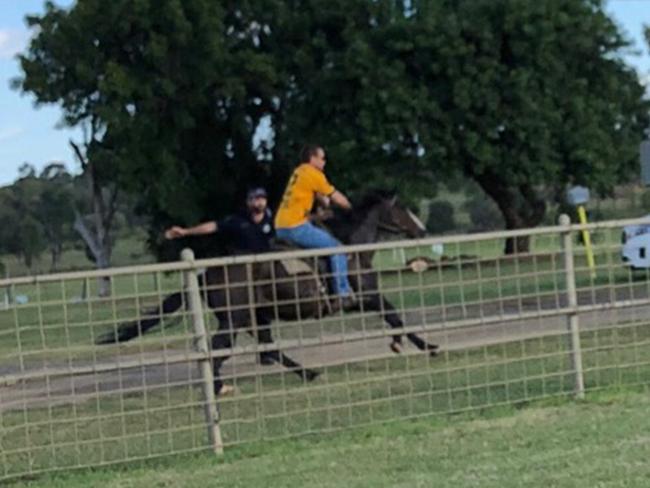 Clinton M Donald riding a horse through Anti Adani protesters at the Clermont Showgrounds.